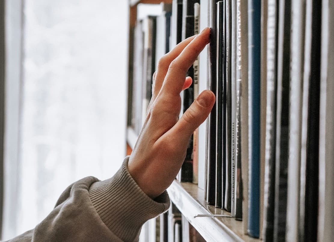 A photo of a hand picking a book in the library